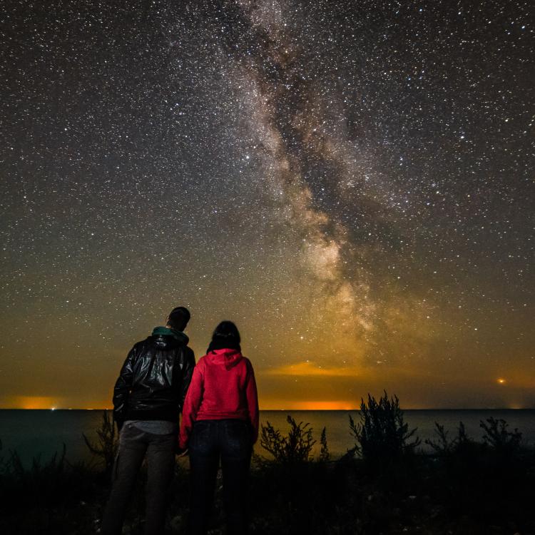Couple on the beach, looking at the Milky Way