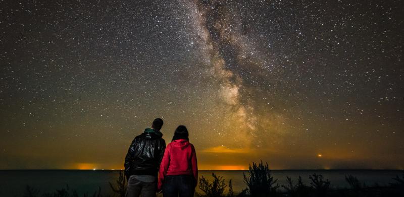 Couple on the beach, looking at the Milky Way